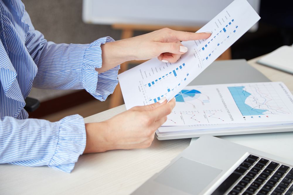 Hands reviewing a printed report beside a laptop