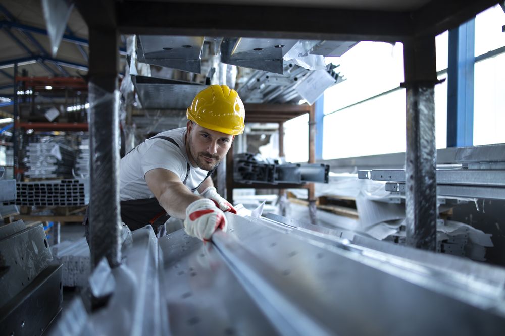A worker handling steel material in a production warehouse