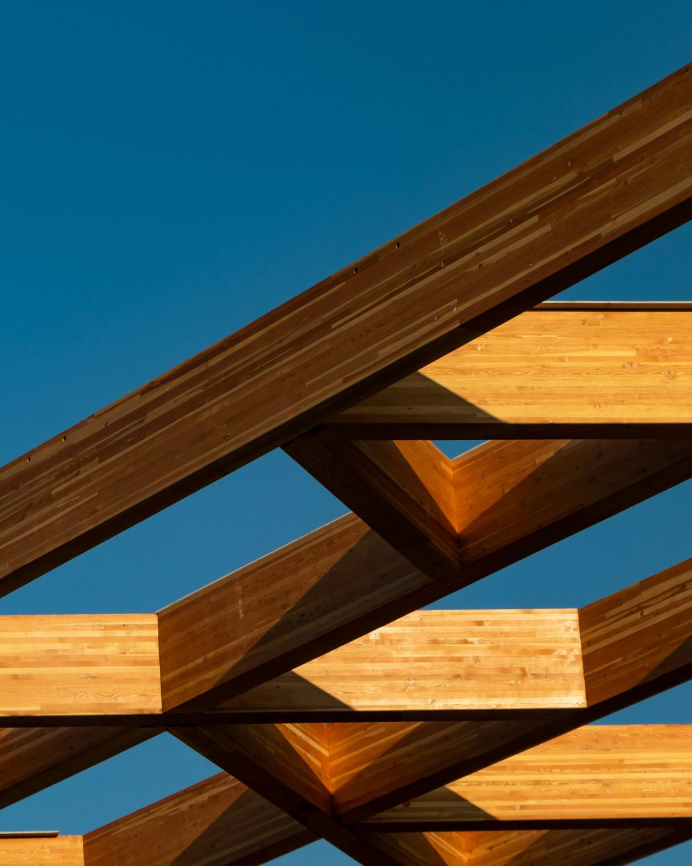 A glulam timber beam junction against a clear sky